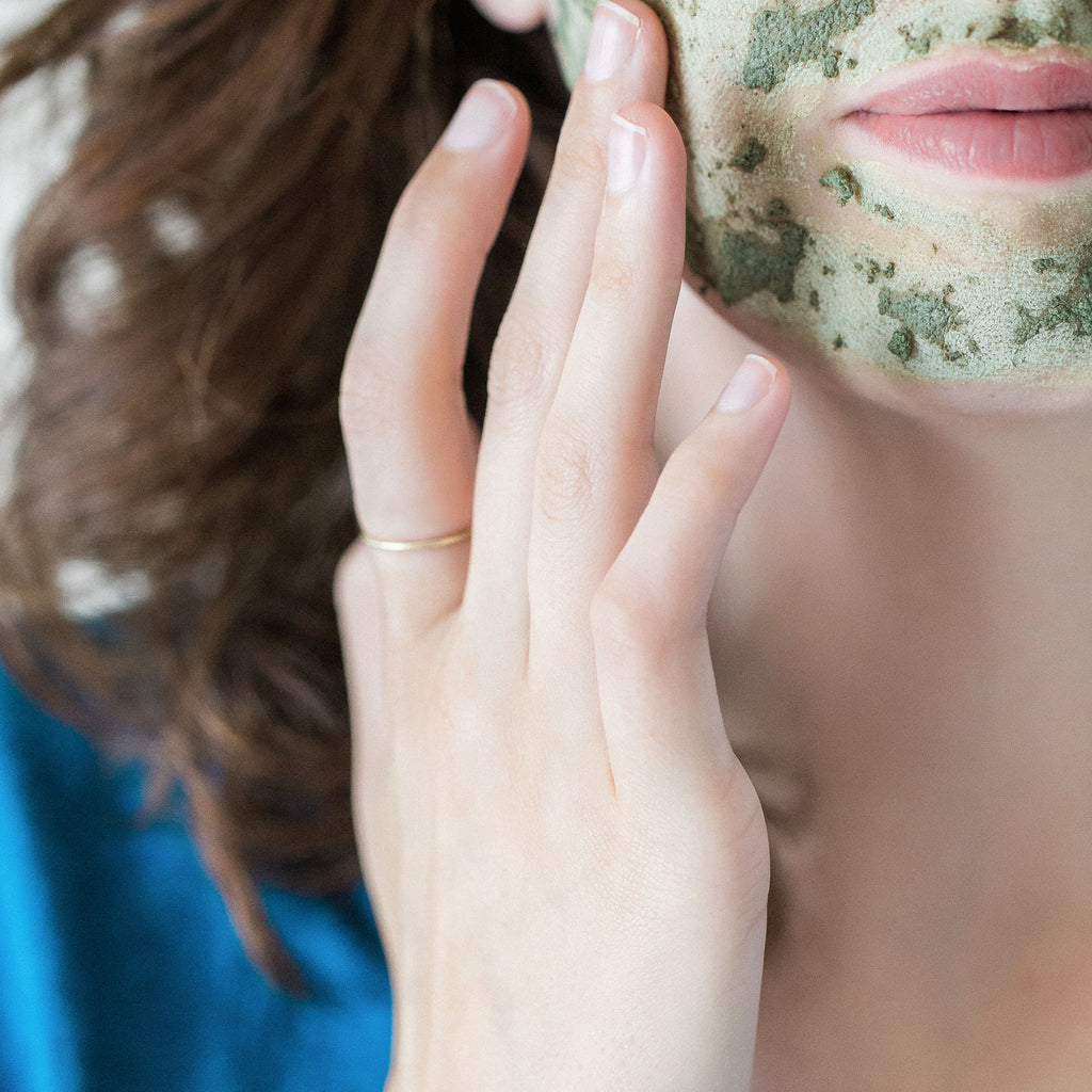 woman with green tea clay mask applied on her face